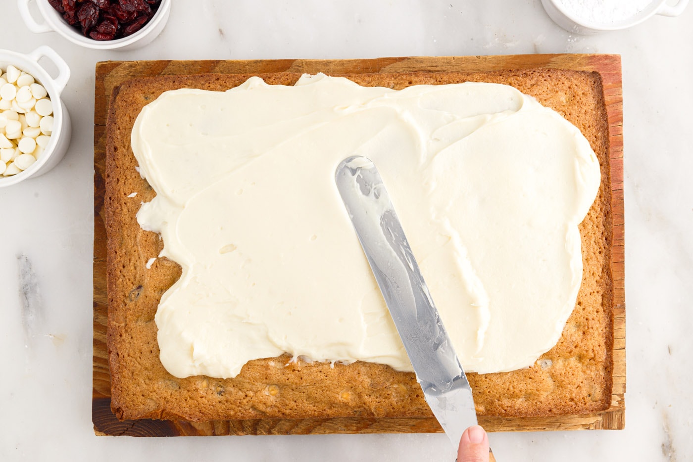 spreading cream cheese frosting over baked blondies