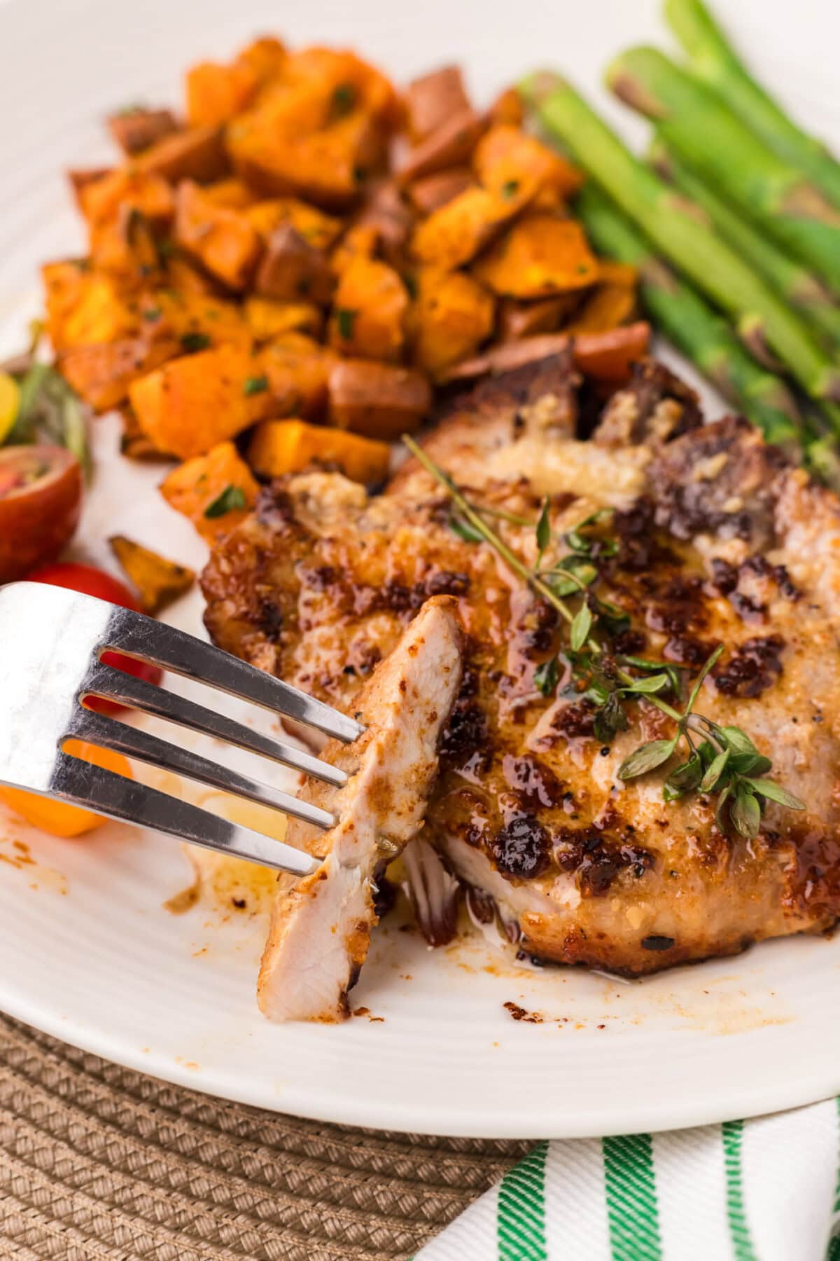 Piece of Garlic Butter Pork Chop on a fork next to a Garlic Butter Pork Chop