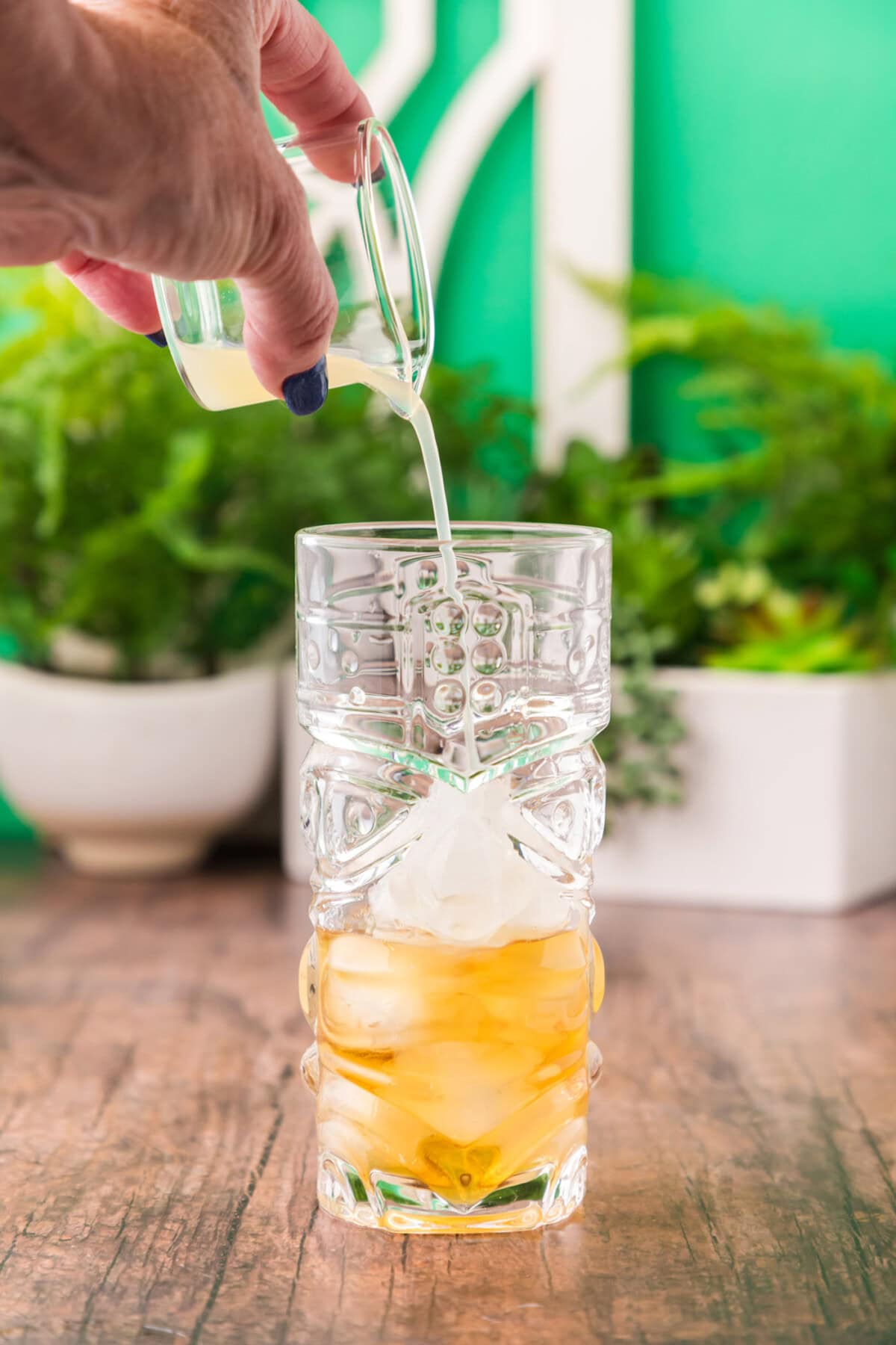 adding lime juice to glass of rum