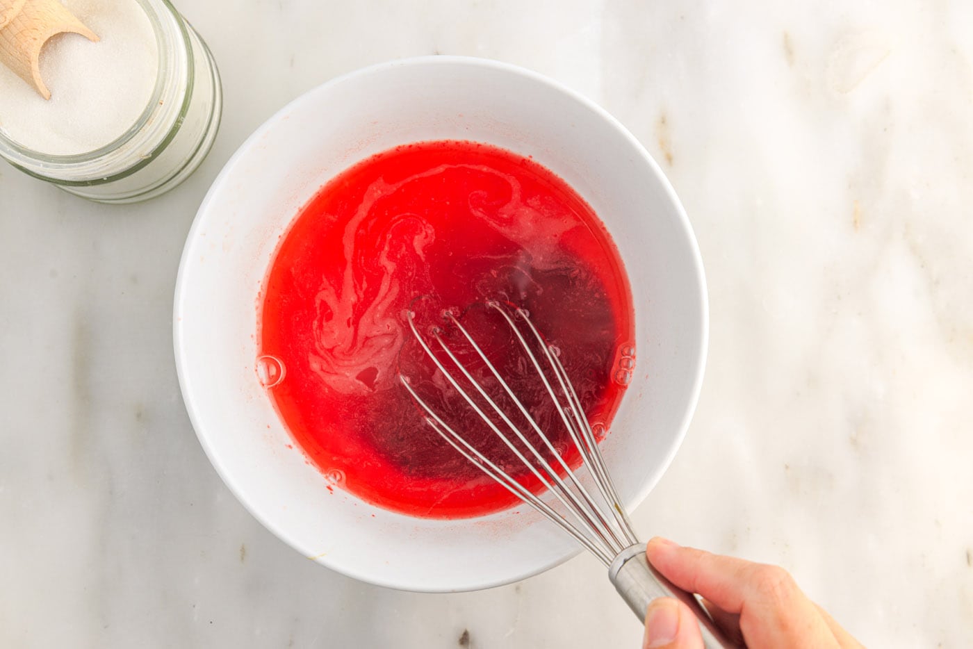 whisking jello powder and sugar with boiling water in a bowl