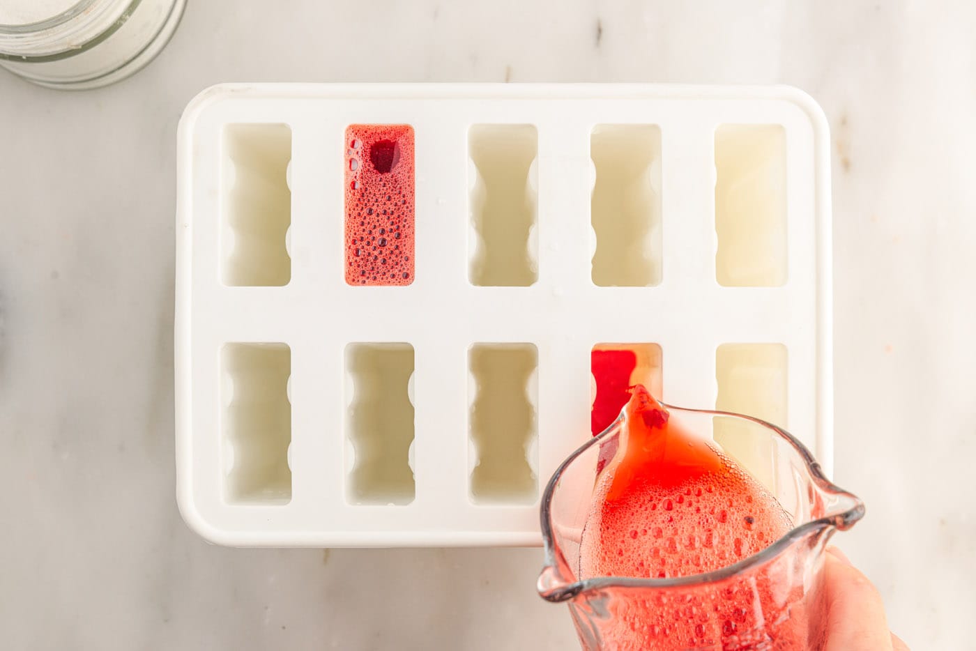 pouring jello mixture into popsicle molds