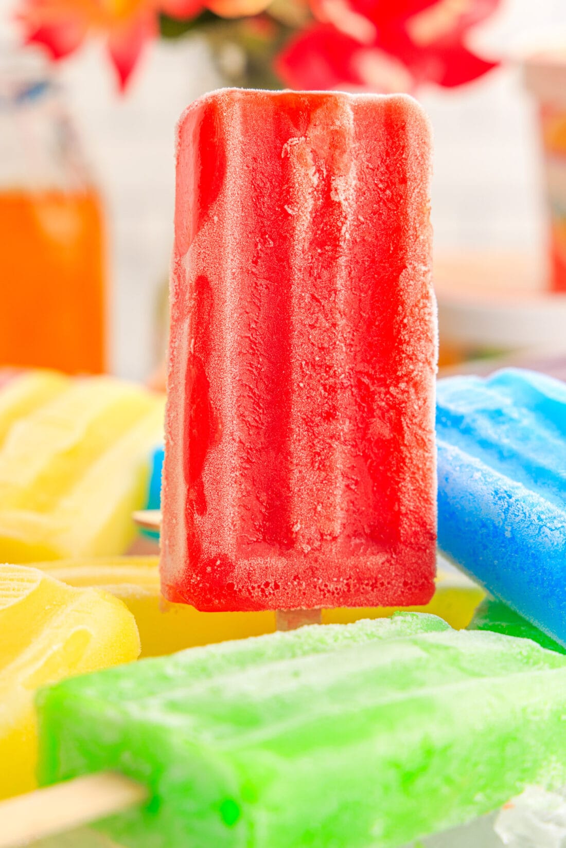 Red Jello Popsicle standing in a bowl of other Jello Popsicles