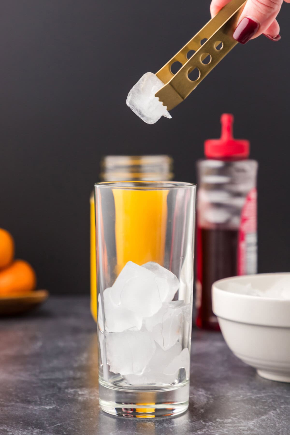 adding ice cubes to highball glass
