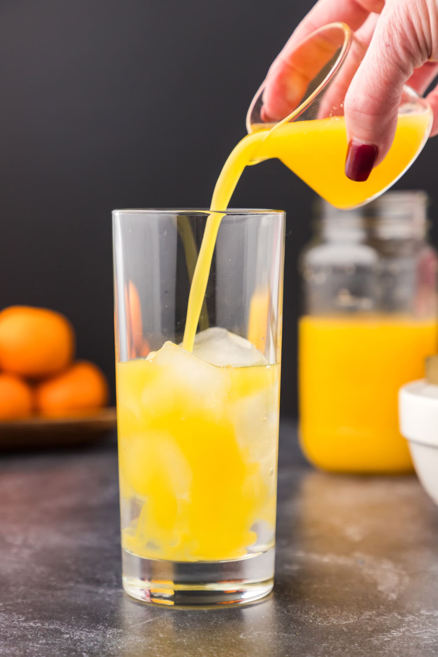 pouring orange juice into cocktail glass with coconut rum