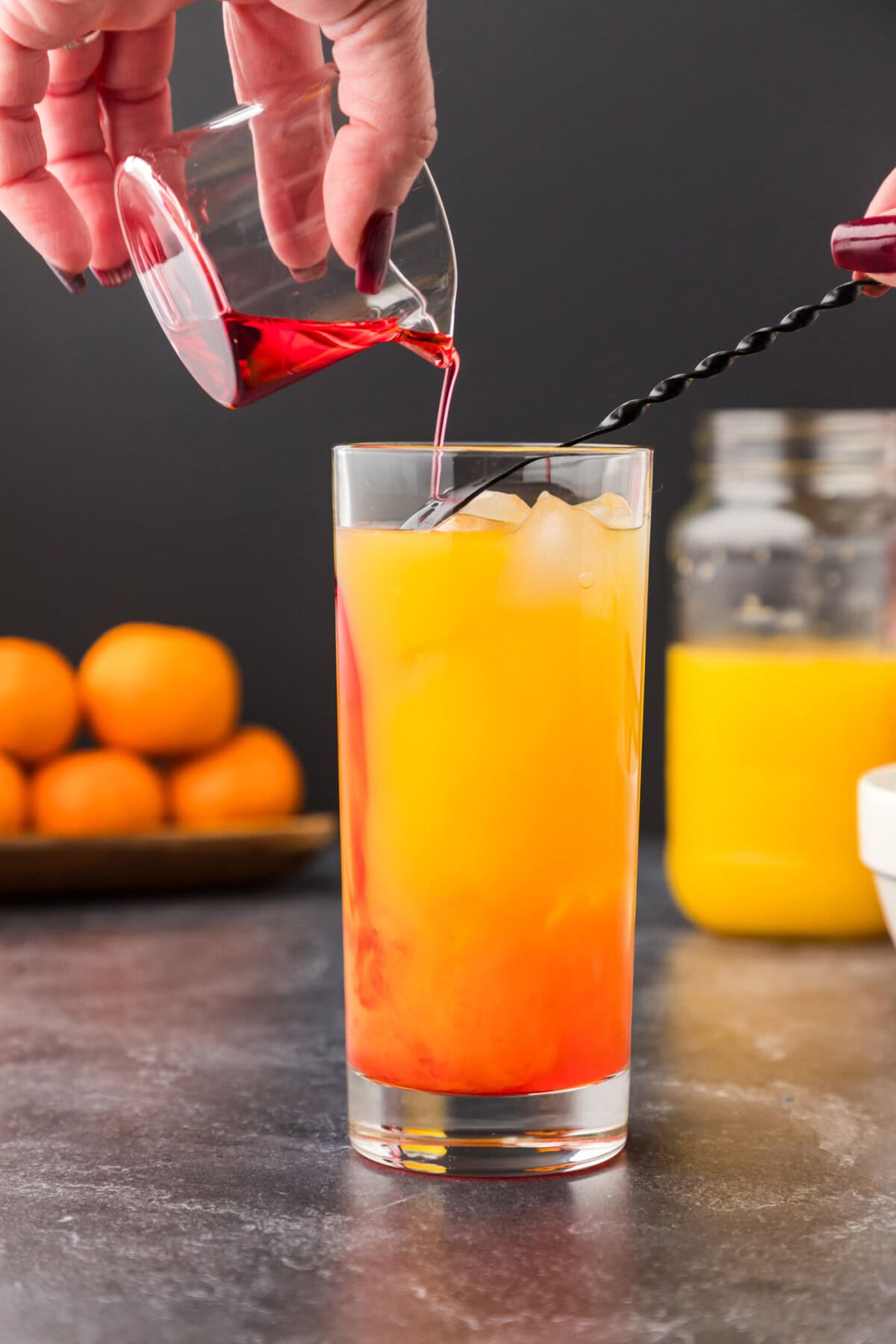 pouring grenadine over a spoon into malibu sunrise