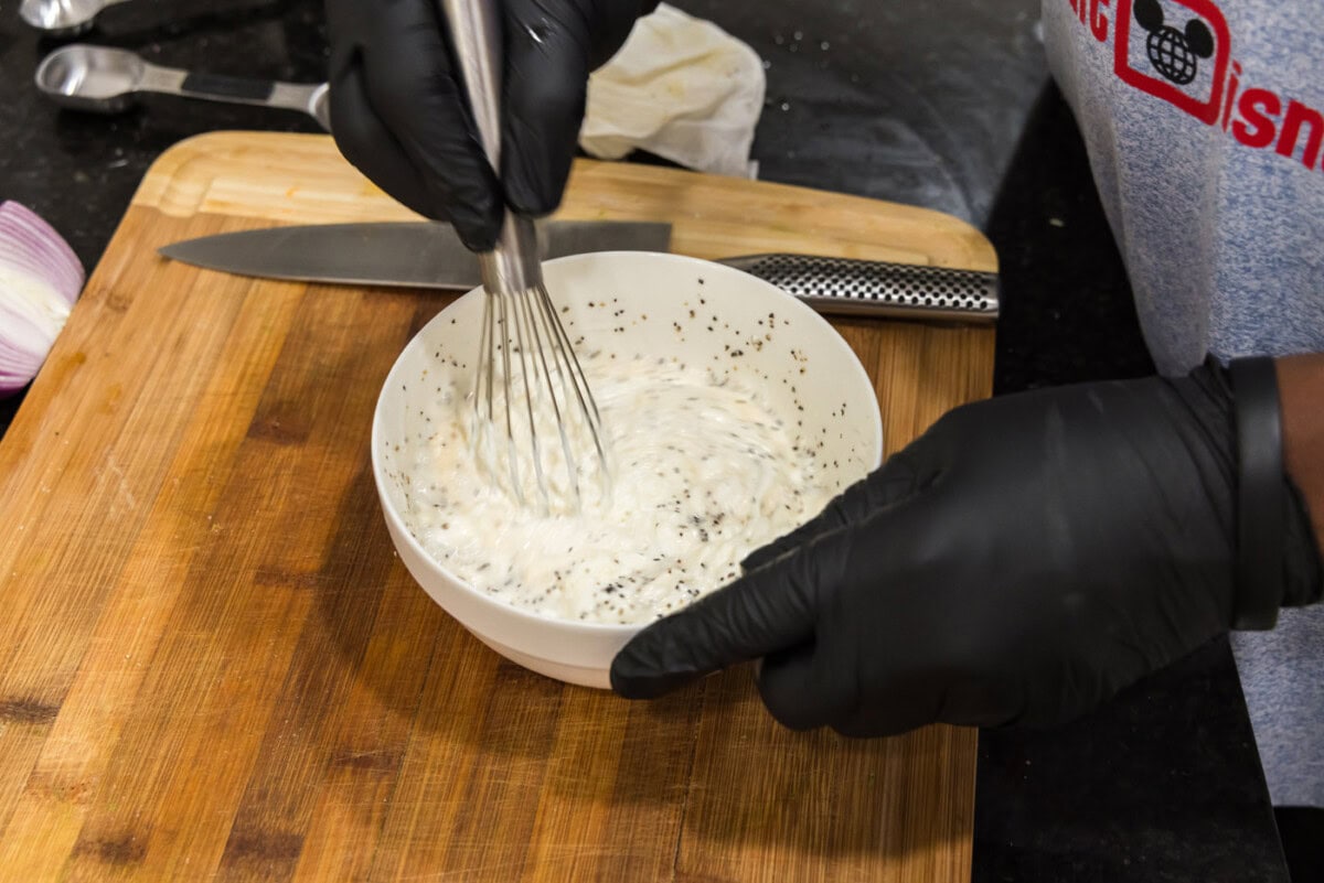 whisking pea salad dressing in a bowl