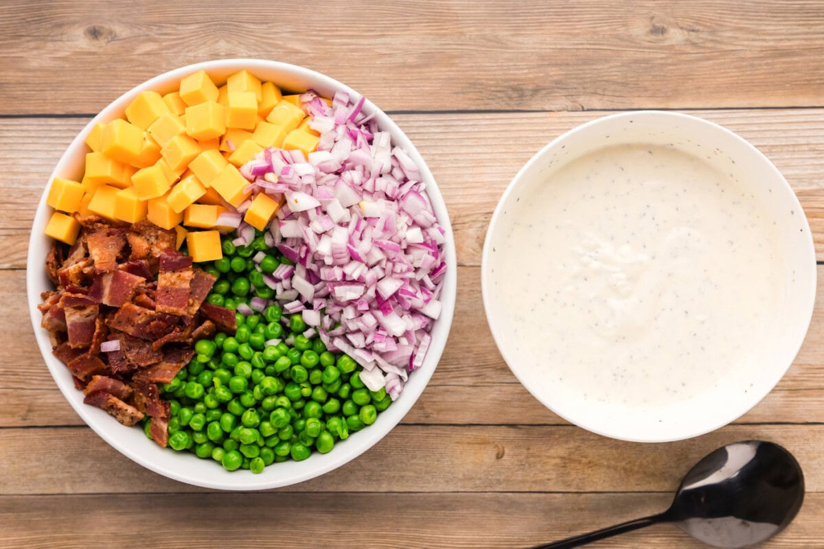 pea salad ingredients in a bowl next to dressing