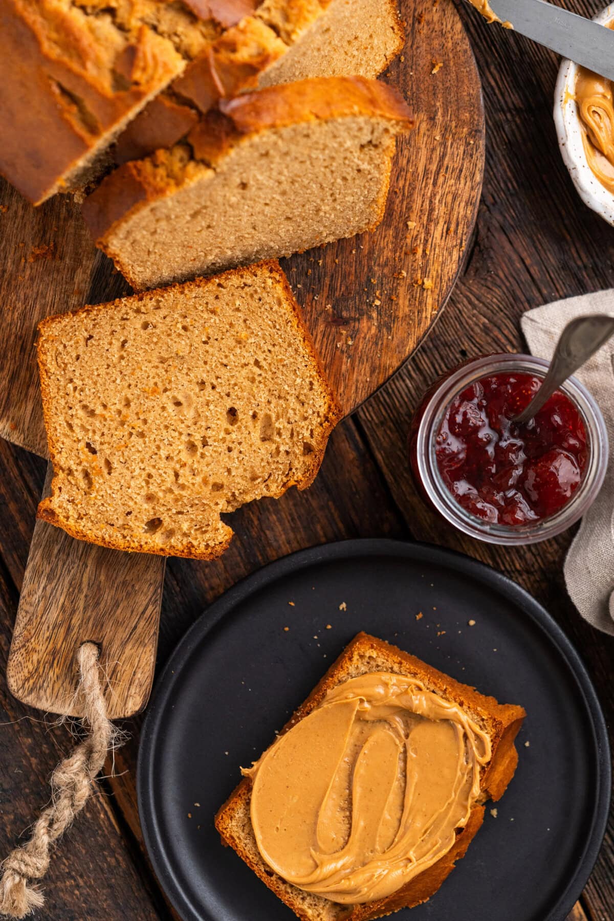 Slices of Peanut Butter Bread on a wooden board with another slice topped with peanut butter