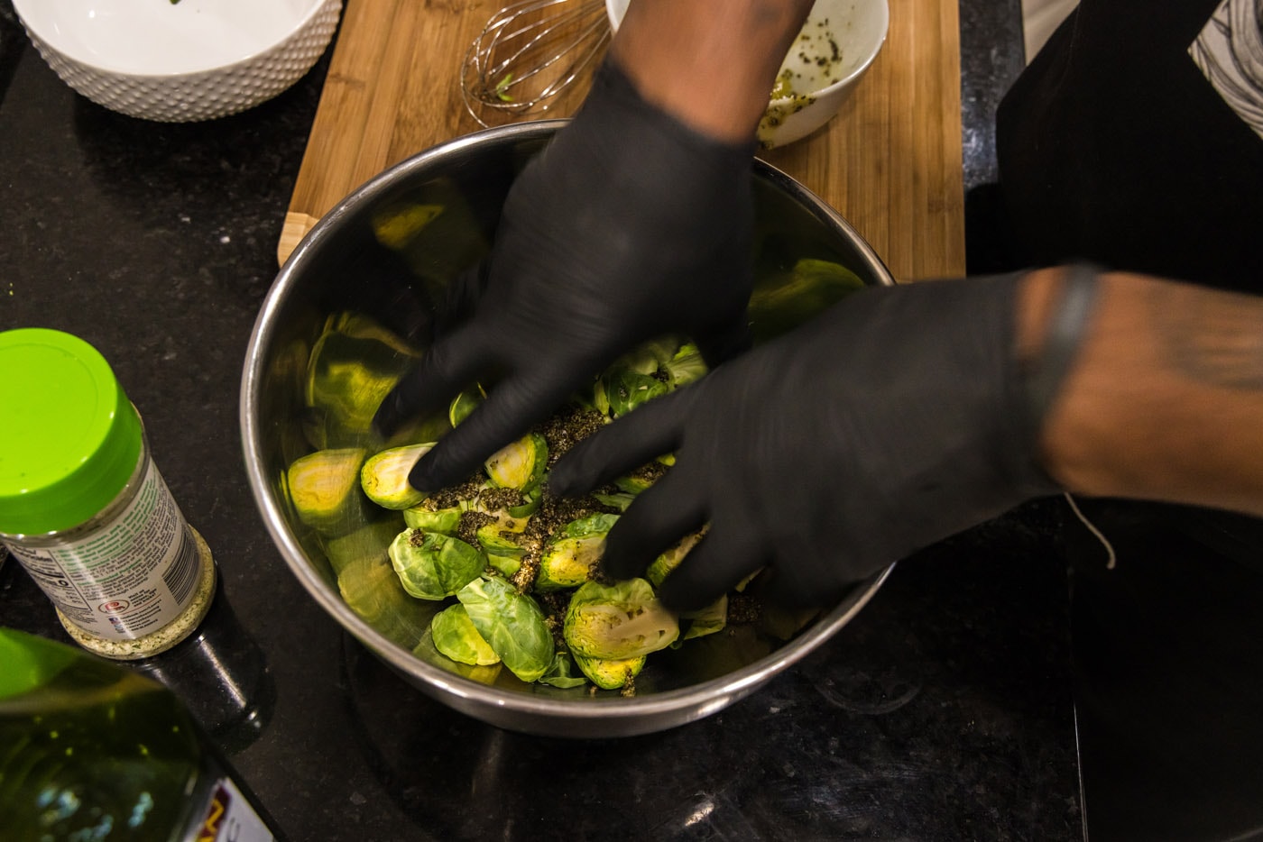 hands mixing brussels sprouts with oil and seasonings