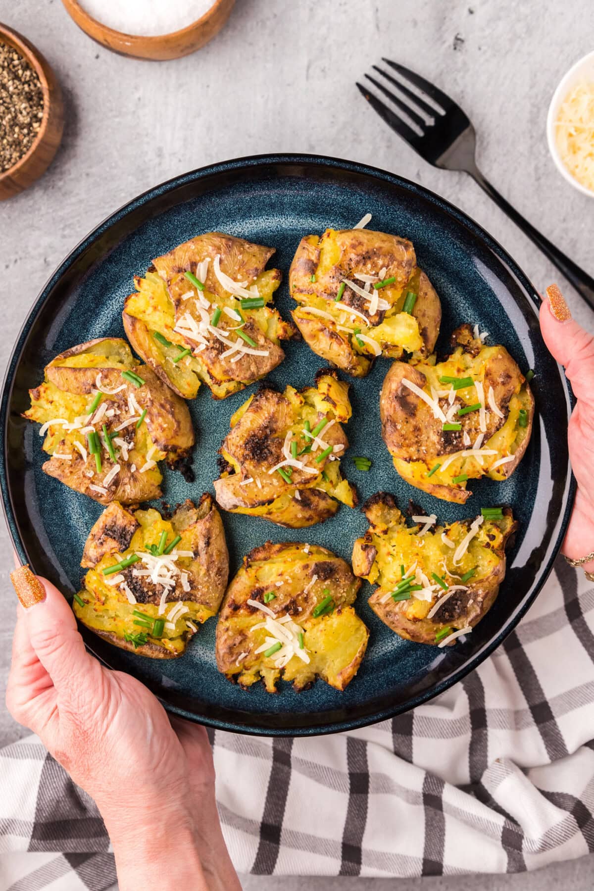 Hands holding up a plate of Smashed Potatoes