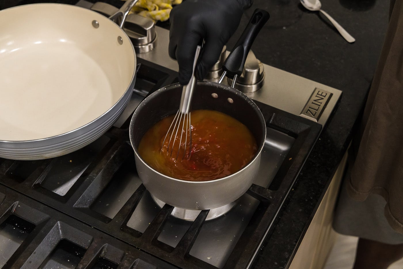 whisking sweet and sour sauce in a saucepan