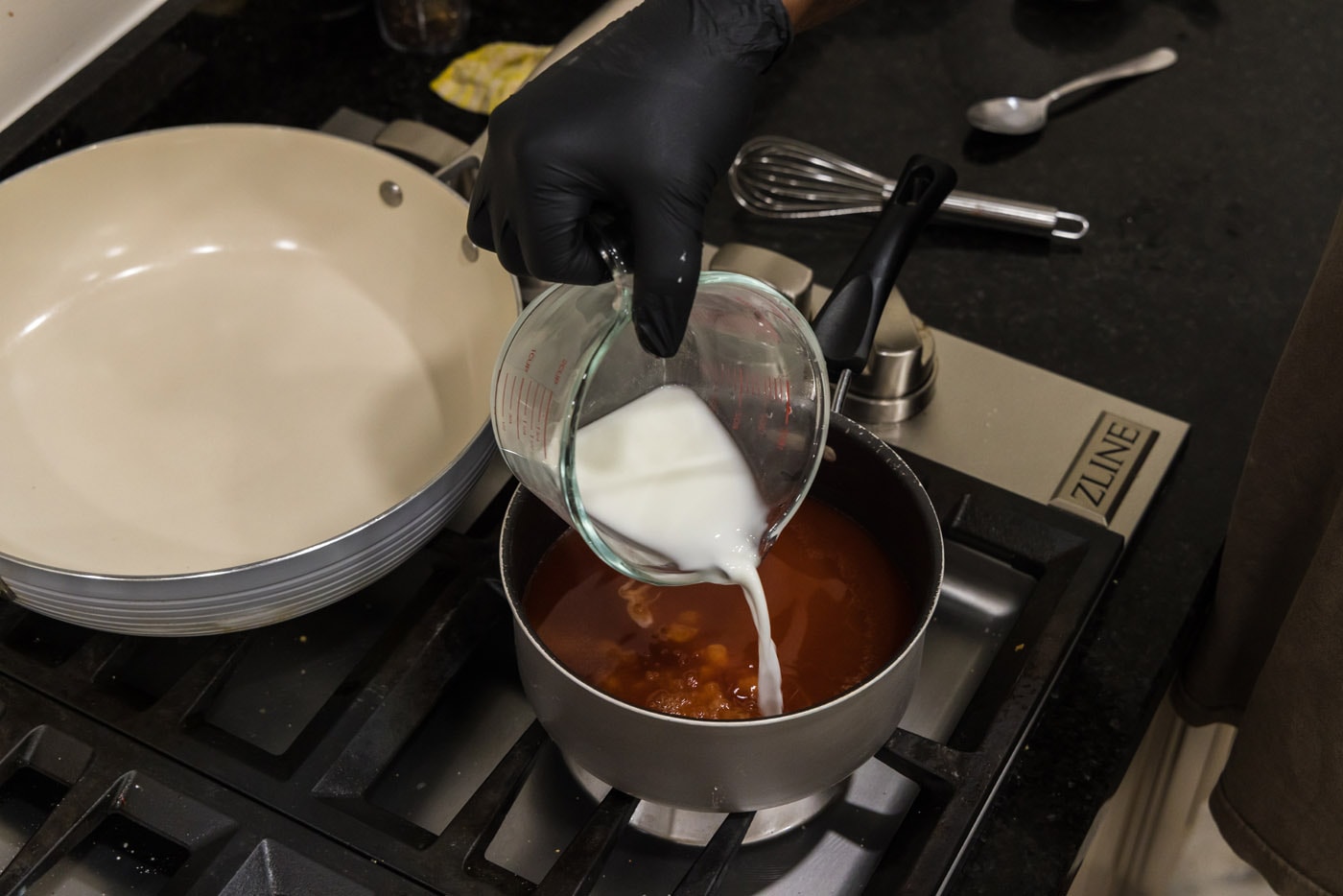 pouring cornstarch slurry into saucepan with sweet and sour sauce