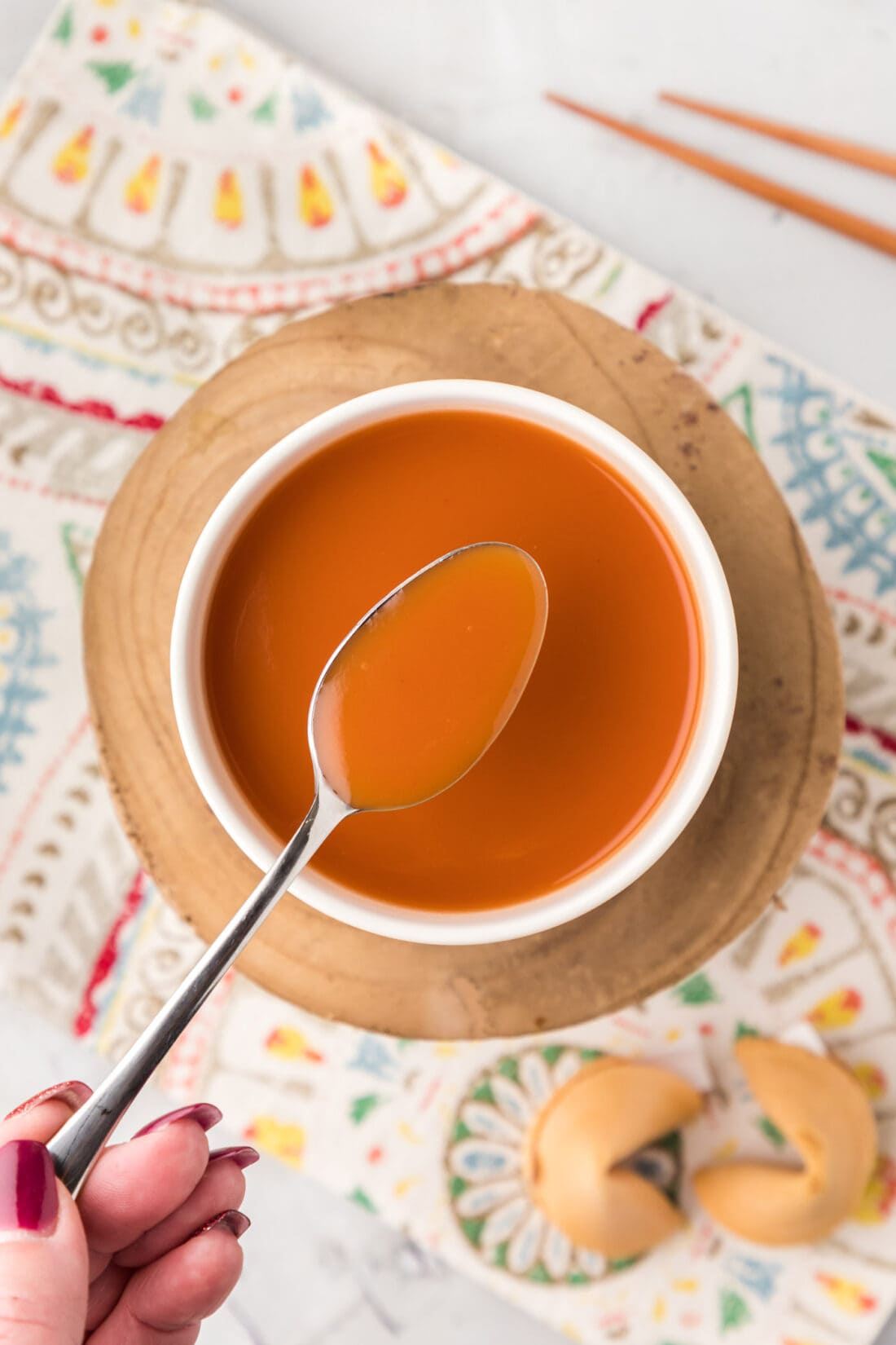 Spoonful of Sweet and Sour Sauce held over a bowl of Sweet and Sour Sauce