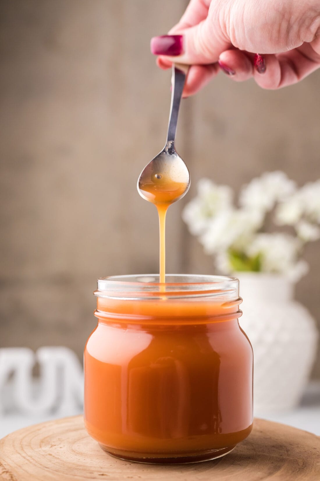 Sweet and Sour Sauce being drizzled off a spoon into a jar