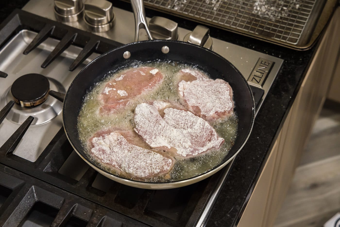 cooking flour coated veal in a skillet of oil