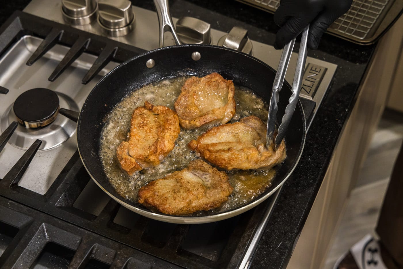 tongs flipping veal chops in skillet