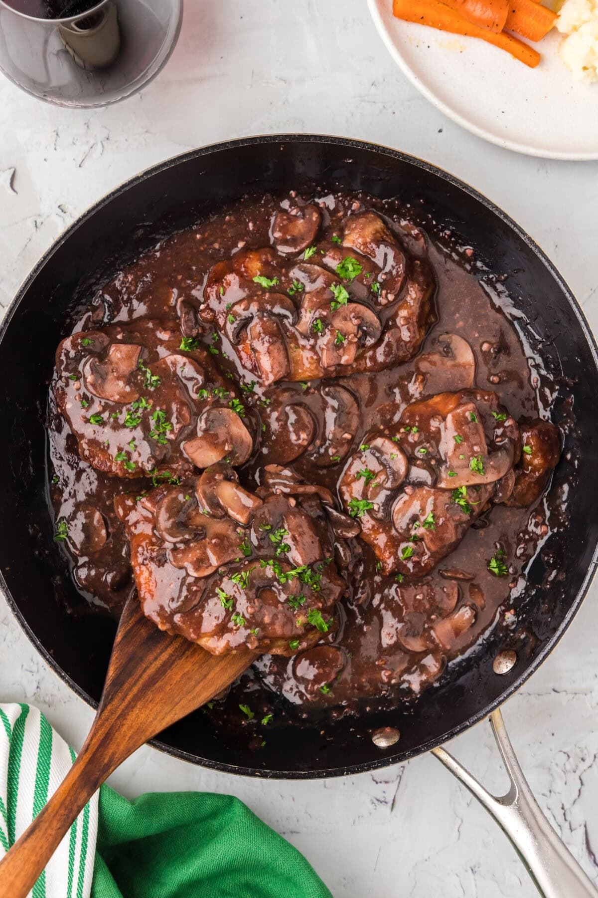 Veal Marsala in a skillet with a wooden spatula 