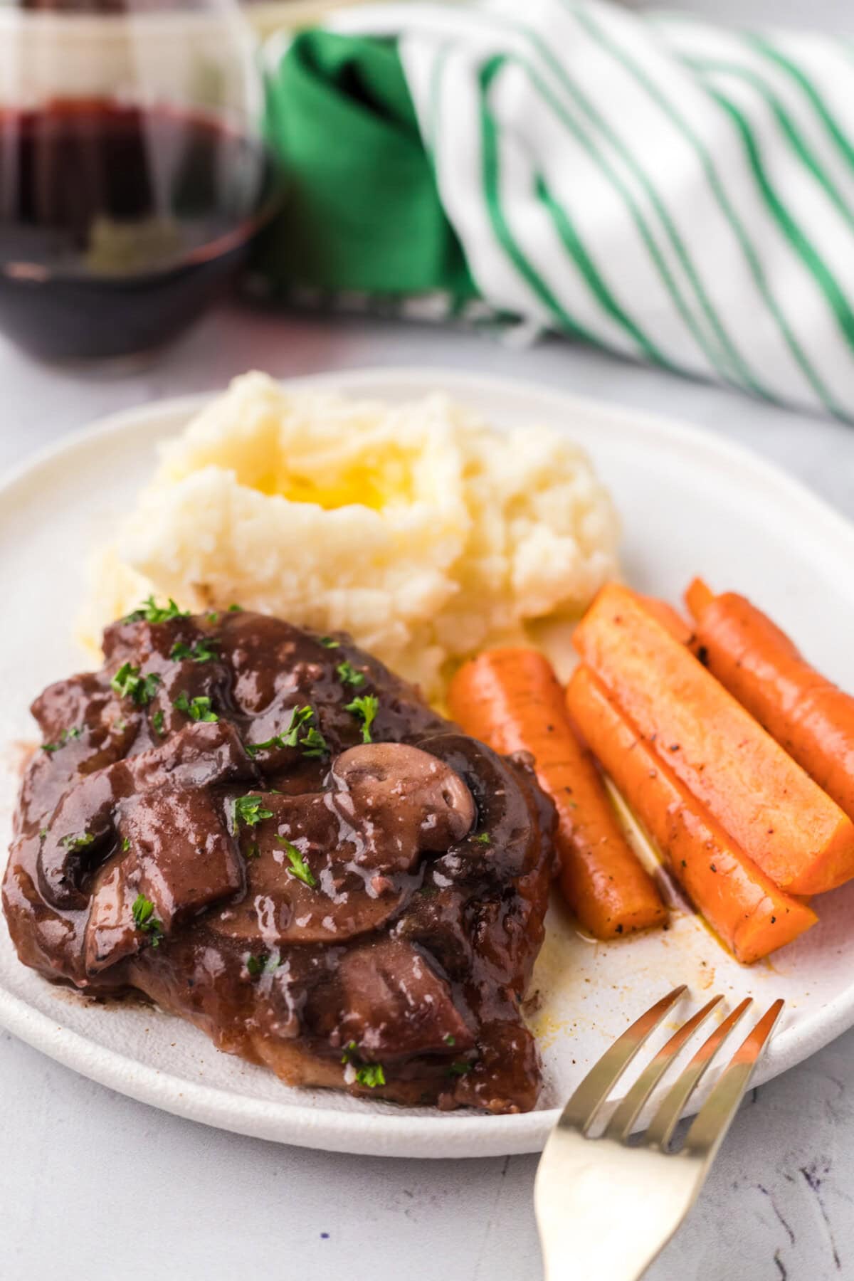 Veal Marsala on a plate with carrots and mashed potatoes