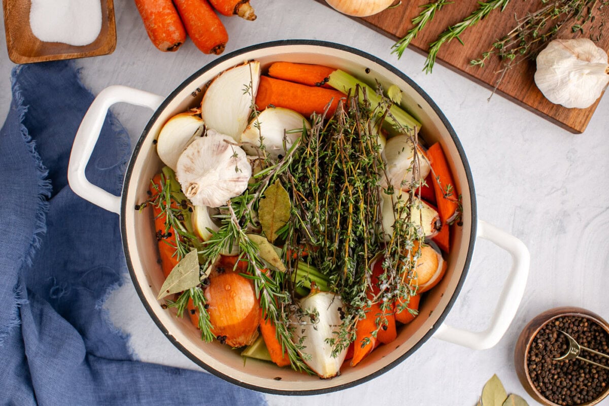 adding water to vegetables and herbs in a stockpot