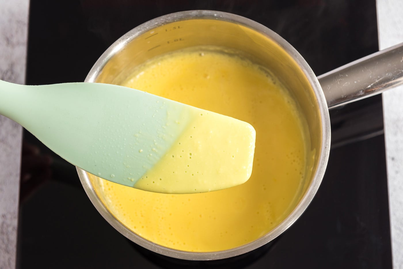 Egg yolk mixture on a spatula showing thickness