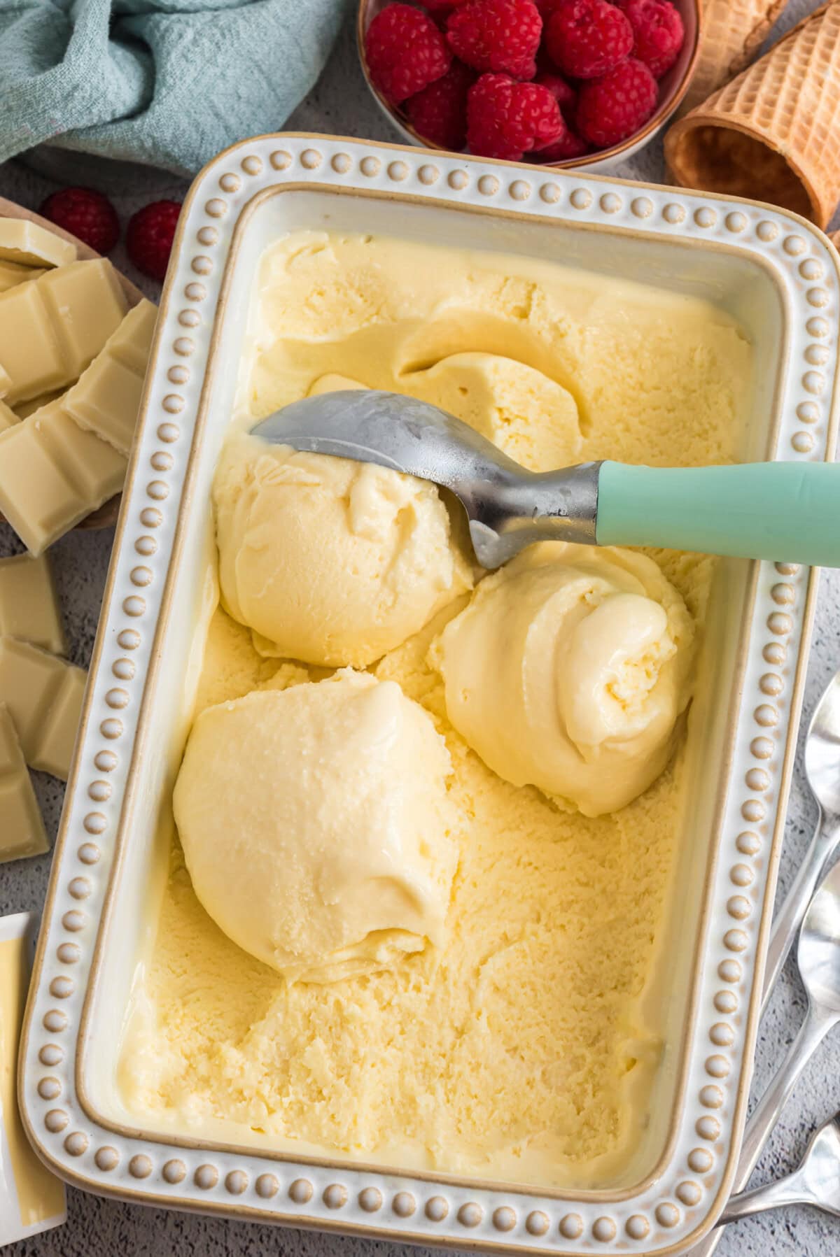 Scoops of White Chocolate Ice Cream in a pan with an ice cream scoop