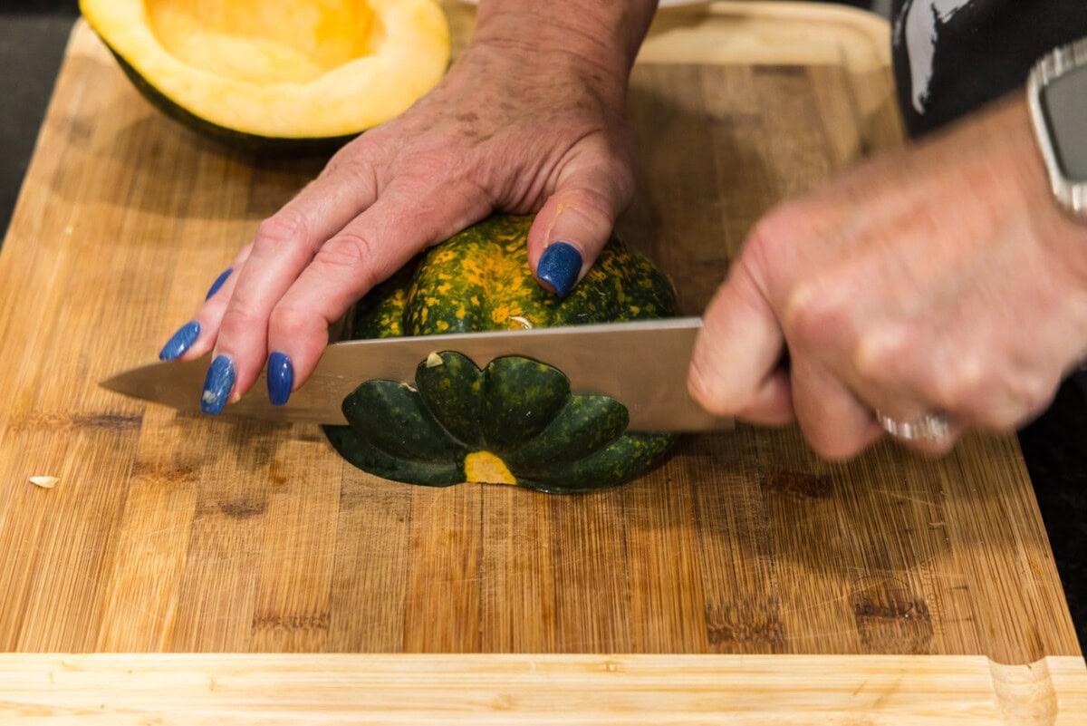 slicing an acorn squash on a cutting board