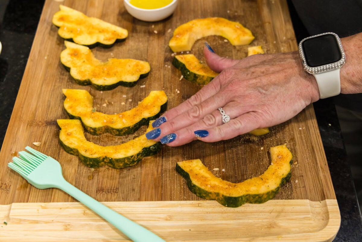 rubbing all purpose seasoning on acorn squash slices