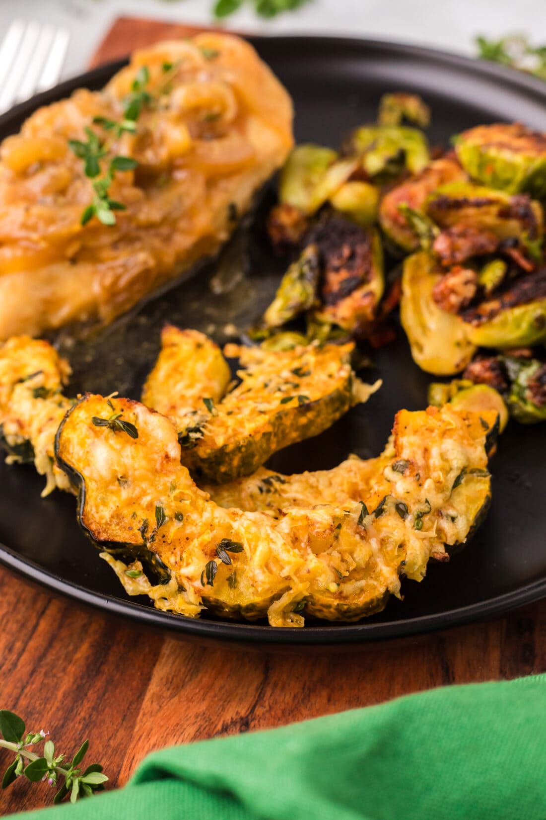 Close up photo of Air Fryer Acorn Squash on a plate with Brussels sprouts and chicken 