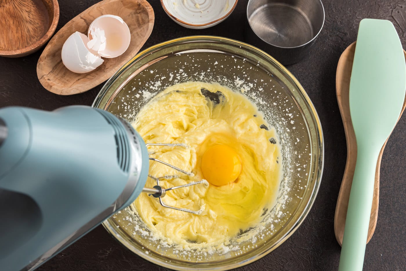 adding eggs to butter mixture in a bowl
