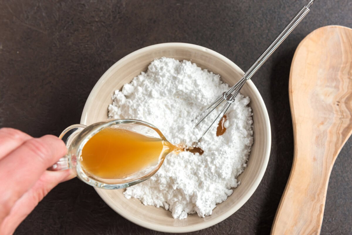 pouring apple cider into powdered sugar