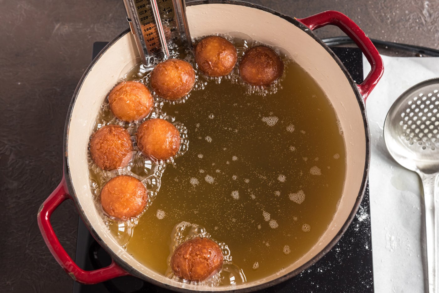 fried donut holes lifted out of oil