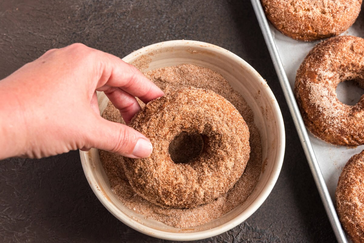 dipping fried donut in cinnamon sugar