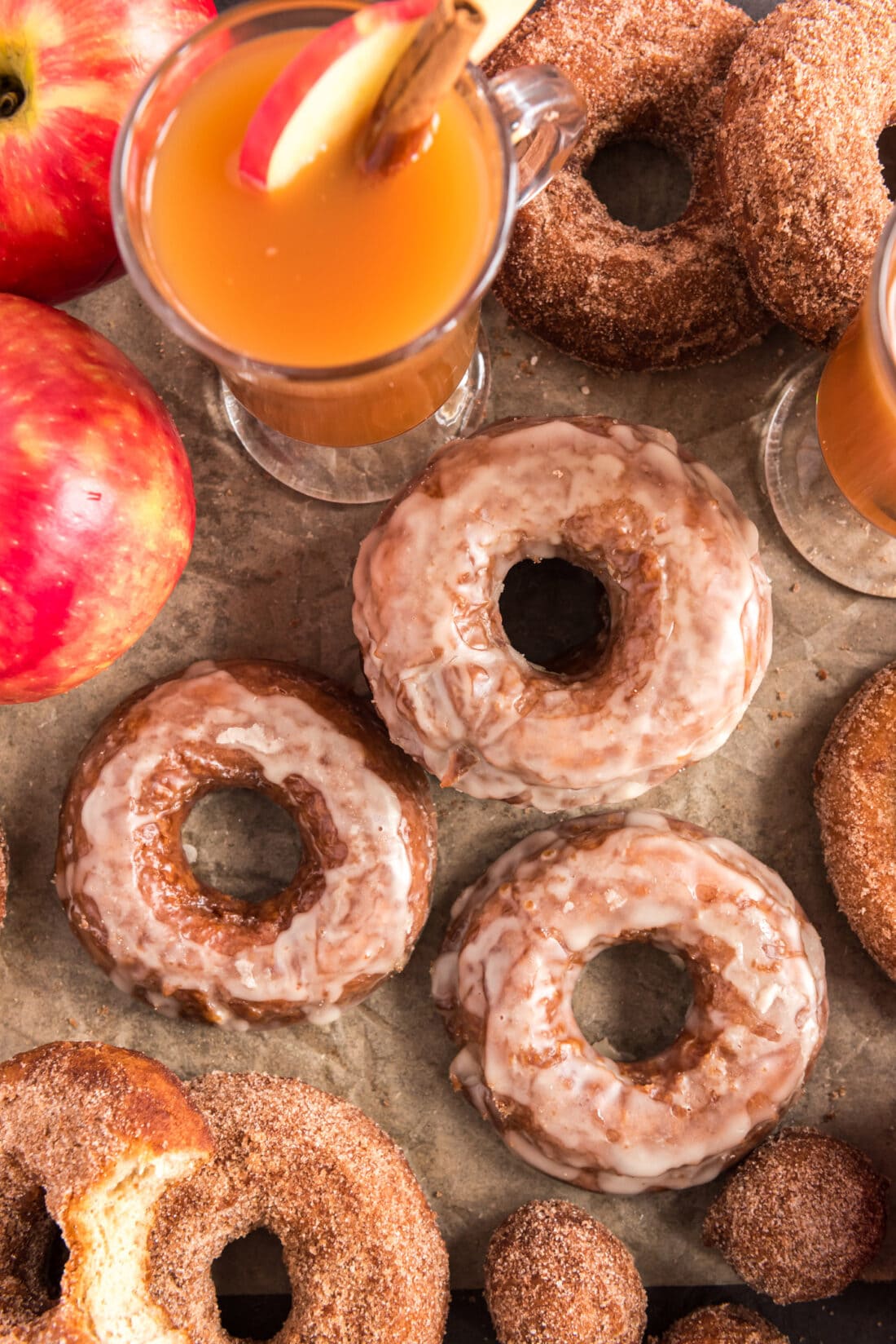 Overhead photo of Apple Cider Doughnuts with apples and apple cider in the background