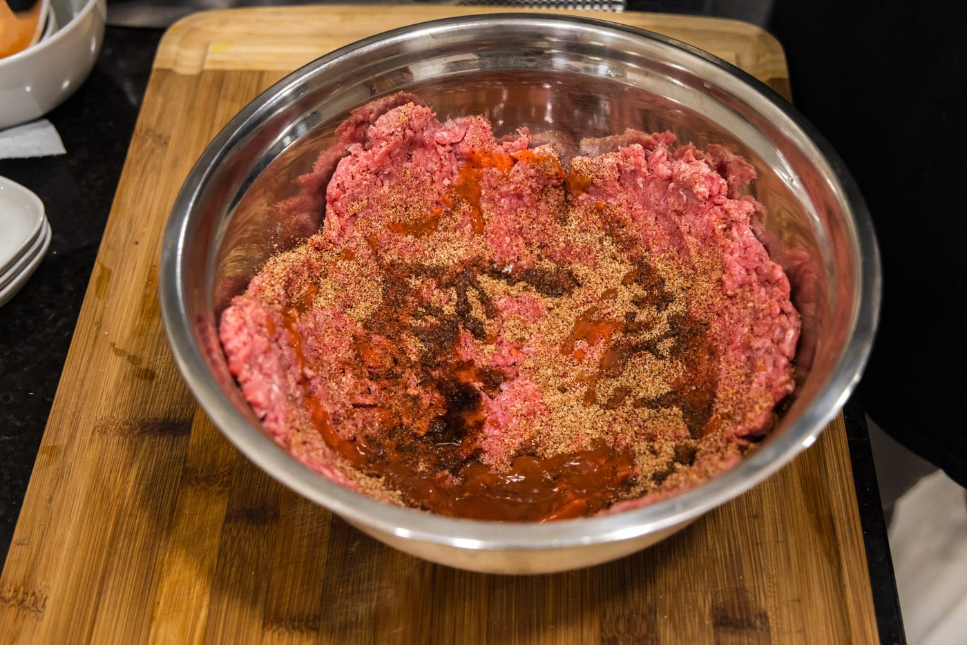 mixing burger meat with seasonings in a bowl