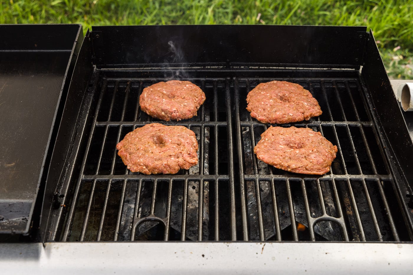 burger patties cooking on a grill grate