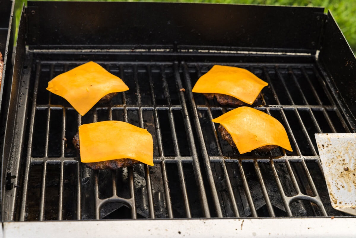 sliced cheddar cheese on top of burger patties