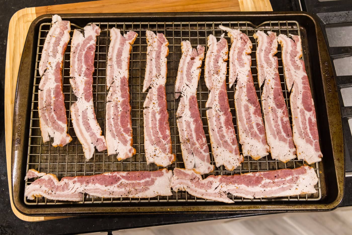bacon strips on a wire rack seasoned with steak seasoning