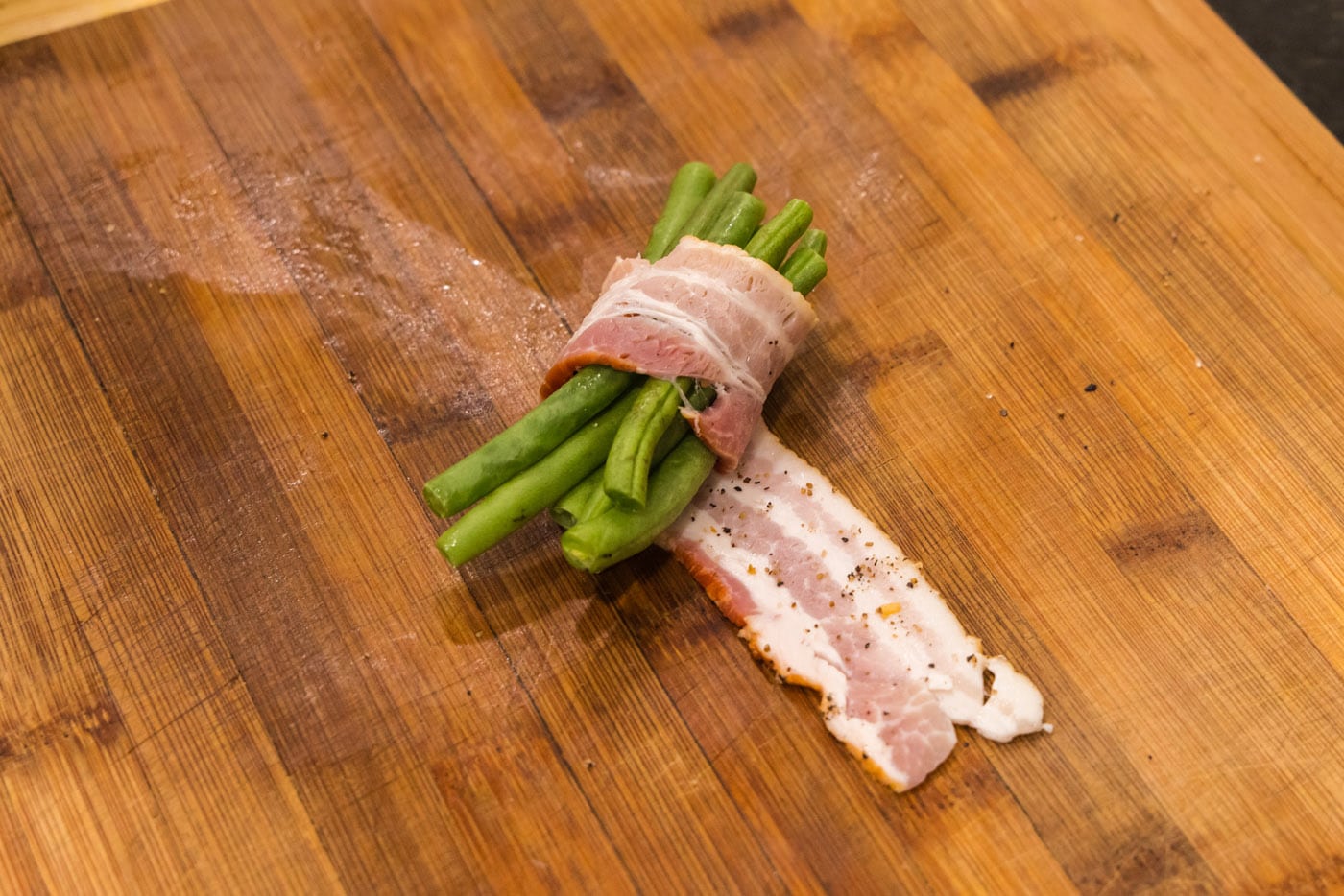 wrapping a bundle of green beans in bacon