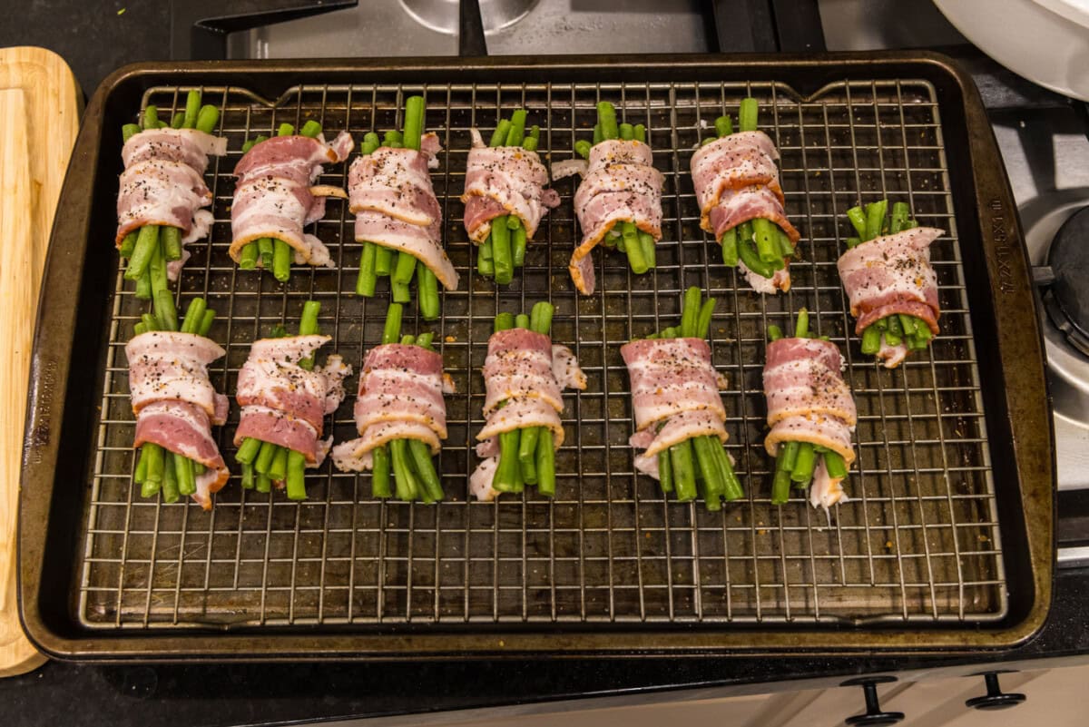 bacon wrapped green bean bundles on a baking sheet