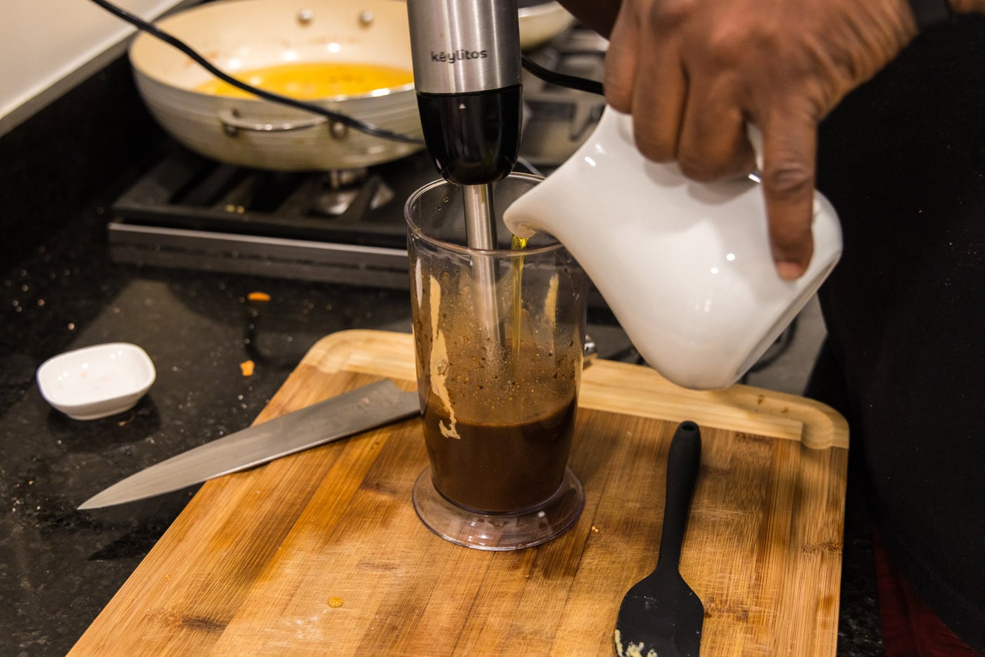 pouring olive oil into balsamic dressing while blitzing with an immersion blender