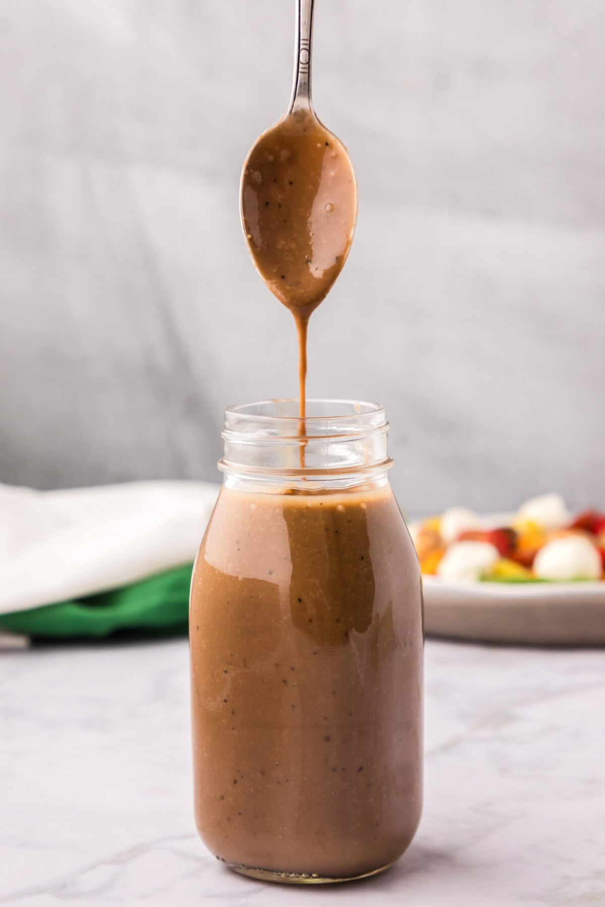 Balsamic Vinaigrette drizzling off a spoon into a jar of Balsamic Vinaigrette