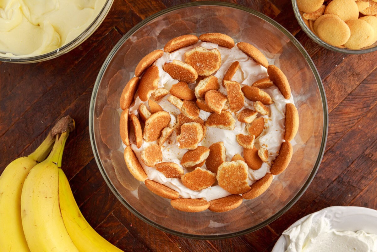 crushed nilla wafers added on top of whipped cream layer in a trifle bowl