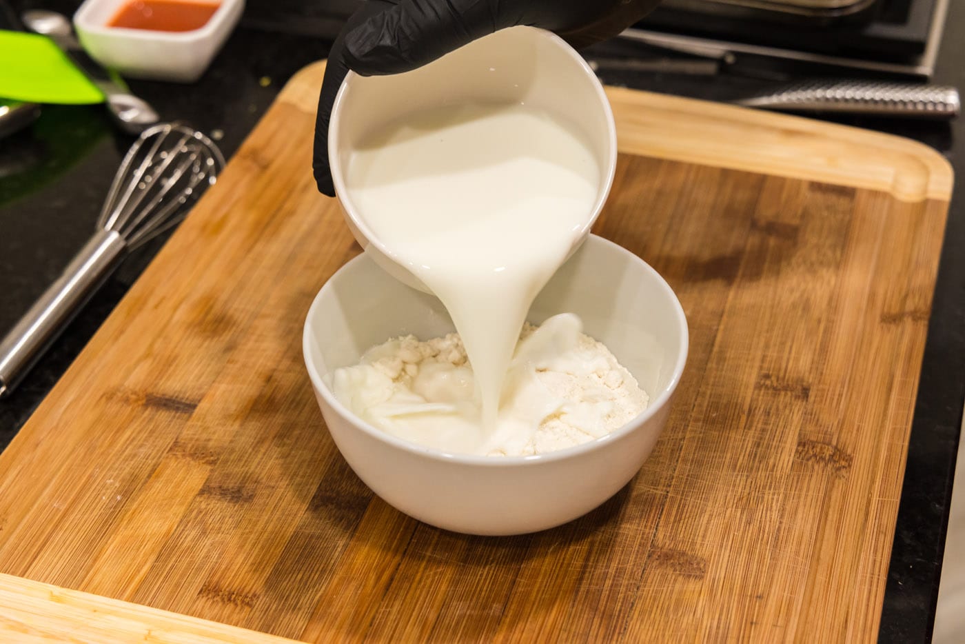 pouring buttermilk into flour in a bowl