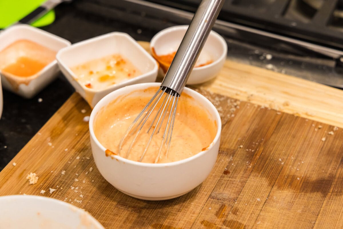 mayo, sriracha, and asian sweet chili sauce in bowl with a whisk