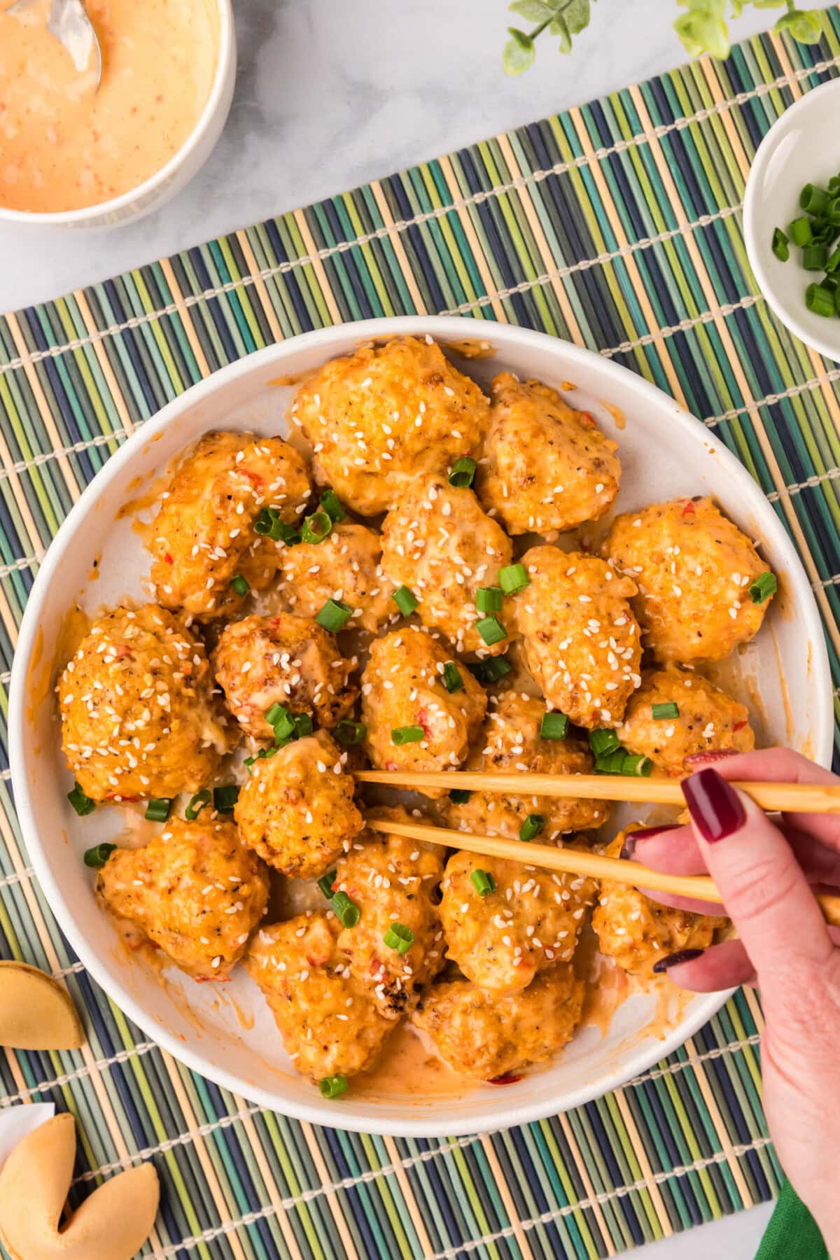 Chopsticks grabbing a piece of Bang Bang Cauliflower off a plate