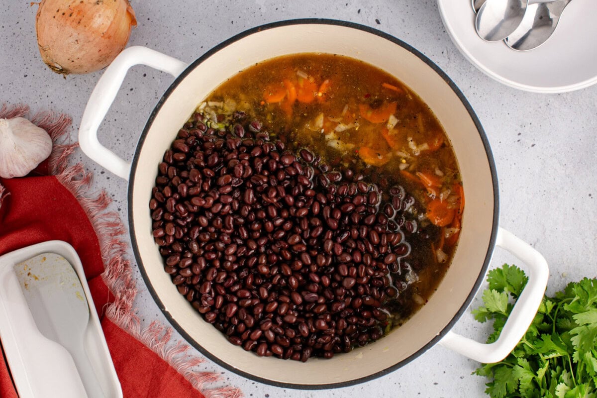 canned black beans and broth added to soup pot of carrots, onion, and celery