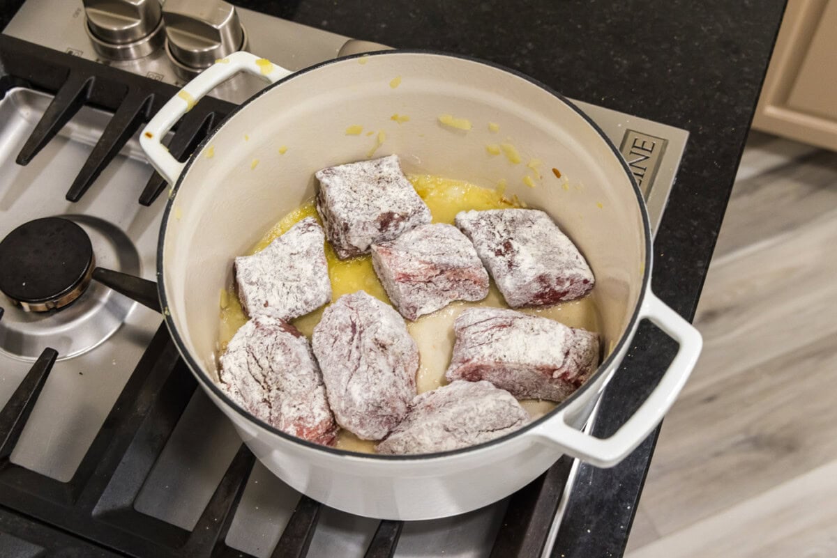 flour dredged beef short ribs searing in a dutch oven