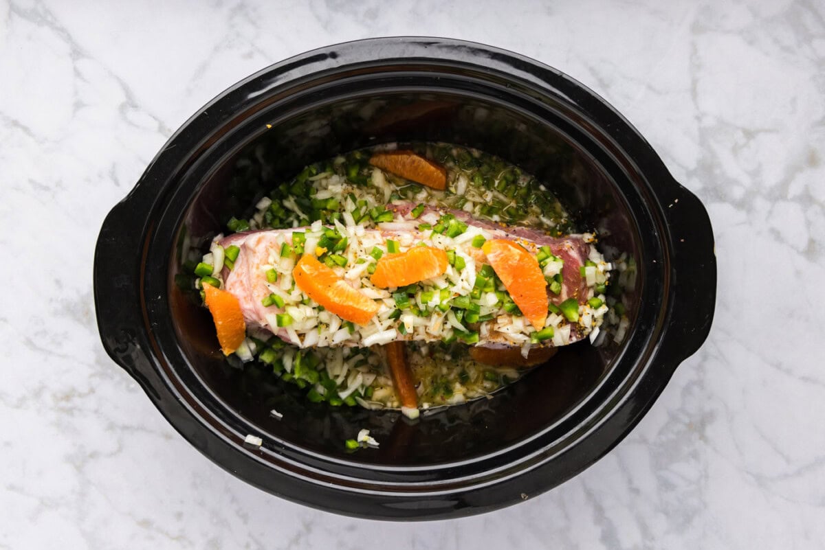 pork shoulder roast with diced jalapenos, onions, and oranges in a crockpot