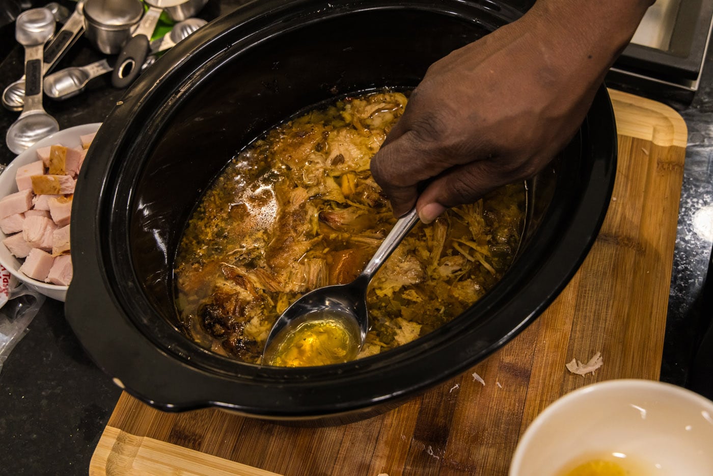 spooning fat from pork shoulder roast in a crockpot