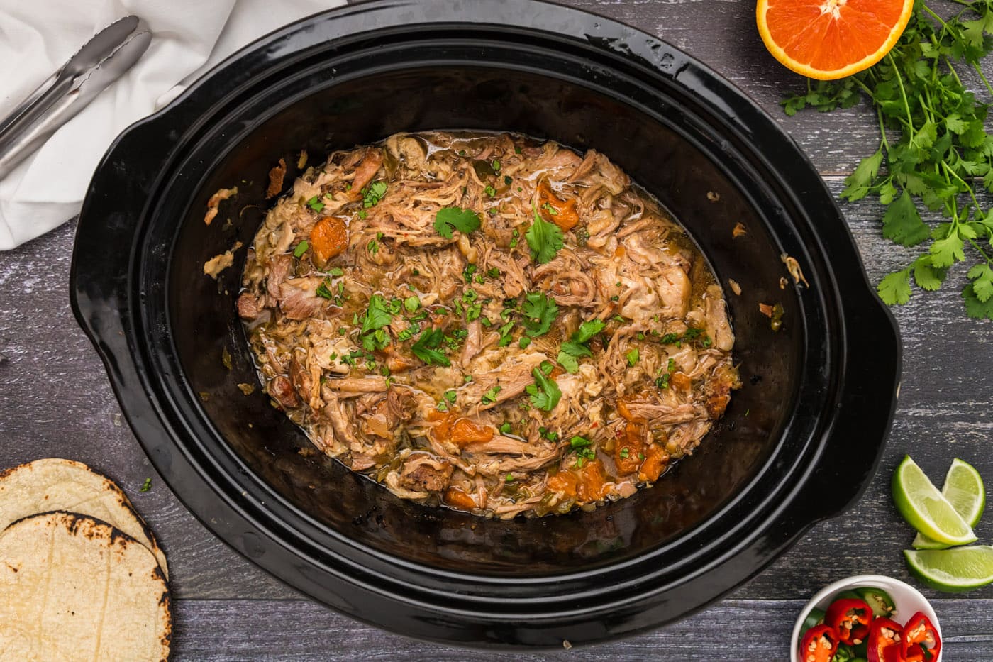 finished shredded carnitas in a crockpot with oranges